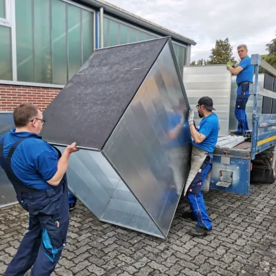 Drei RINKE-Mitarbeiter laden großen Luftkanal auf einen Anhänger